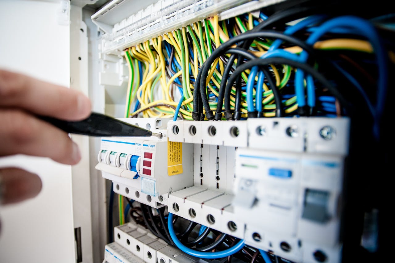 about-us Hand of electrician working on a circuit breaker panel with colorful wires, ensuring safe electrical connections.